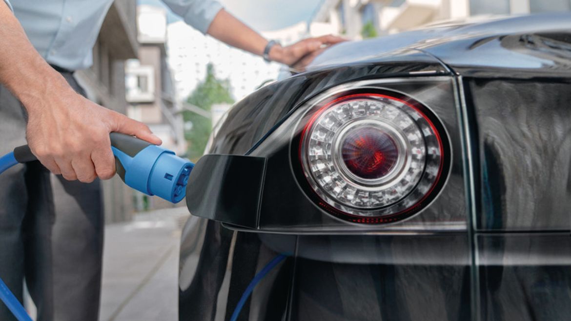Uomo che ricarica un veicolo elettrico